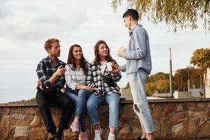 kaffe tid. grupp av ung glad vänner den där är utomhus har roligt tillsammans foto