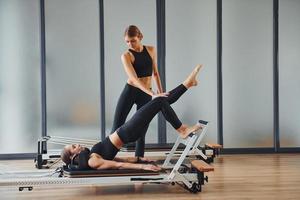 lär ny övningar. två kvinnor i sportigt ha på sig och med smal kroppar ha kondition yoga dag inomhus tillsammans foto