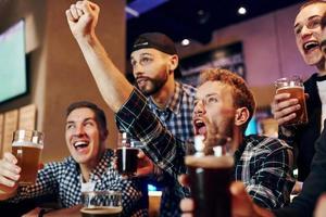 fotboll fläktar fira seger. grupp av människor tillsammans inomhus i de pub ha roligt på helgen tid foto