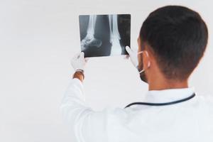 läkare med röntgen. ung stilig man stående inomhus mot vit bakgrund foto