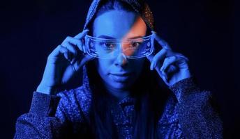 porträtt av ung flicka den där är i glasögon i blå neon belysning foto