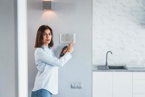 kvinna är inomhus kontrollerande smart Hem teknologi foto