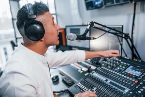 miljö de Utrustning. ung man är inomhus i de radio studio är upptagen förbi utsända foto