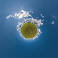 grön mycket liten planet i blå himmel med skön moln med omvandling av sfärisk panorama 360 grader. krökning av Plats. foto