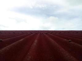 närbild av röd tak omslag. kaklade tak med himmel bakgrund foto