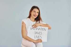 ung kvinna i mask är sitter efter vaccin injektion inomhus foto