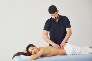 ung kvinna är liggande ner när man håller på med massage av henne tillbaka på spa foto