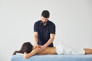 ung kvinna är liggande ner när man håller på med massage av henne kropp på spa foto