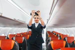 säkerhet instruktioner. ung Flygvärdinnan på de arbete i de passagerare flygplan foto