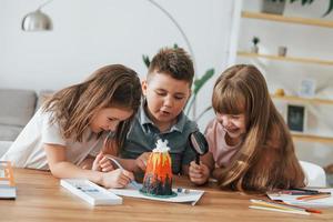 byggnad vulkan från plasticine. barn har roligt i de inhemsk rum på dagtid tillsammans foto