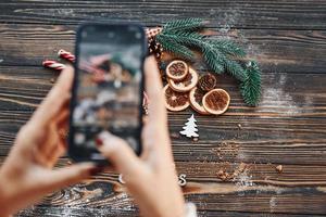 kvinna innehav telefon. jul bakgrund med Semester dekoration foto