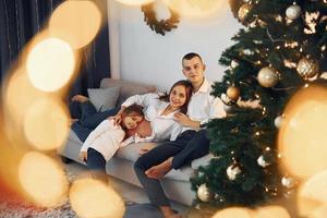 med jul träd. Lycklig familj fira högtider inomhus tillsammans foto