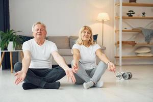 håller på med yoga. senior man och kvinna är tillsammans på Hem foto