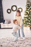 aktiva tid utgifter. liten bror och syster är på jul dekorerad rum tillsammans foto