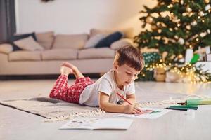 teckning förbi använder sig av penna. liten pojke är i rum med jul träd är på de golv foto