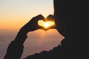 silhuett. kvinna formning en hjärta form under soluppgång. Gud är kärlek begrepp. hjärta form. berg turism. som visar kärlek kärlek och känslor, tillägnande och hoppas. foto