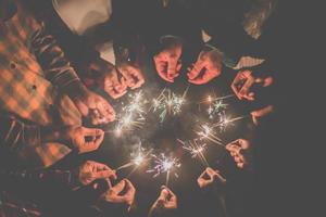grupp av ung vänner njut av med brinnande sparkler i händer tillsammans foto