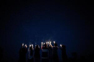 grupp av ung vänner innehav och spela med brand brinnande sparklers foto