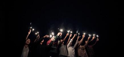 grupp av ung vänner innehav och spela med brand brinnande sparklers foto