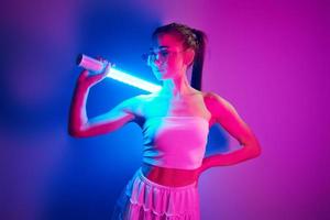 trogen stil. modern ung kvinna stående i de studio med neon ljus foto