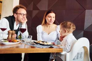 ung kille, kvinna och liten pojke. inomhus av ny modern lyx restaurang foto