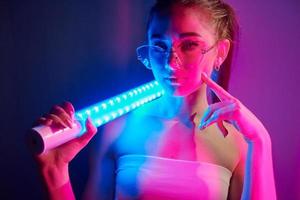 med belysning Utrustning. modern ung kvinna stående i de studio med neon foto