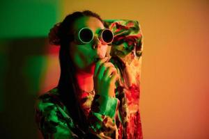i retro pilot glasögon. modern ung kvinna stående i de studio med neon ljus foto