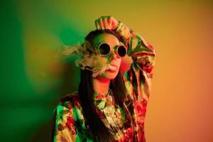 rökning, aktivitet. modern ung kvinna stående i de studio med neon ljus foto