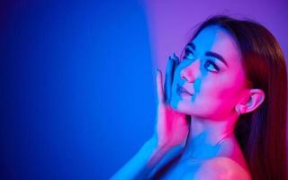 stänga upp se. modern ung kvinna stående i de studio med neon ljus foto