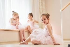 flicka sitter på de golv. liten ballerinor framställning för prestanda förbi praktiserande dansa rör sig foto