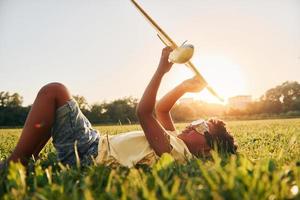 i glasögon med leksak plan. afrikansk amerikan unge ha roligt i de fält på sommar dagtid foto