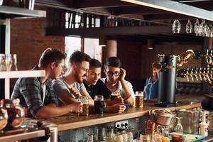 människor i tillfällig kläder Sammanträde i de pub och dricka öl foto