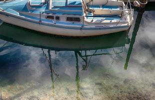 gammal segelbåt reflekterande i en hamn pir docka foto