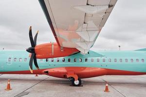 orange och blå färgad. turboprop flygplan parkerad på de bana på dagtid foto