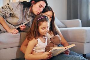 läsning bok tillsammans. kvinna lesbisk par med liten dotter utgifterna tid tillsammans på Hem foto