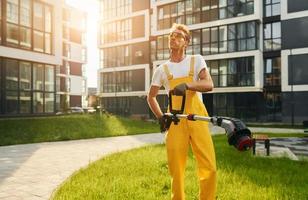 man skära de gräs med gräsmatta mover utomhus i de gård foto