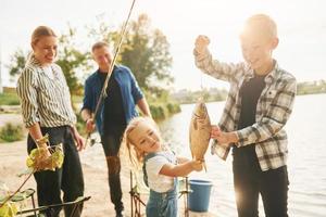 stor fånga. far och mor med son och dotter på fiske tillsammans utomhus på sommartid foto