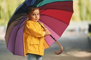 liten pojke i gul täcka ha en promenad utomhus i de parkera efter de regn foto