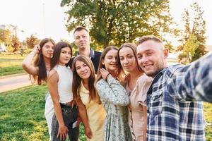 tar en selfie. grupp av ung människor ha en fest i de parkera på sommar dagtid foto