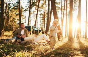 flicka är har en promenad. Lycklig familj av far, mor och liten dotter är i de skog foto