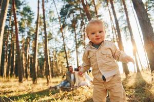 liten flicka är löpning. Lycklig familj av far, mor och liten dotter är i de skog foto