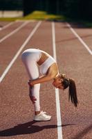 stretching övningar. ung kvinna i sportigt kläder är håller på med kondition utomhus foto