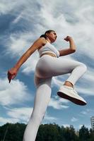 molnig himmel. ung kvinna i sportigt kläder är utövar utomhus foto