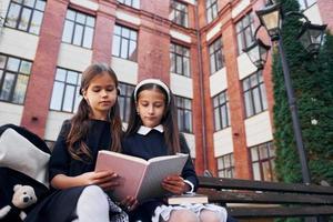 med böcker. två skol är utanför tillsammans nära skola byggnad foto