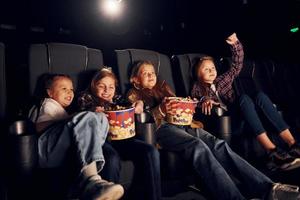 Sammanträde på de svart säten. grupp av barn Sammanträde i bio och tittar på film tillsammans foto