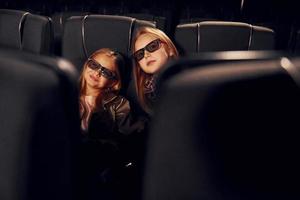 två barn Sammanträde i bio och tittar på film tillsammans foto