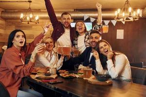 fotboll fans. grupp av ung vänner Sammanträde tillsammans i bar med öl foto