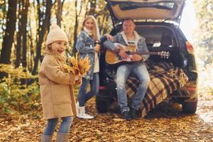 med akustisk gitarr. Lycklig familj är i de parkera på höst tid tillsammans foto