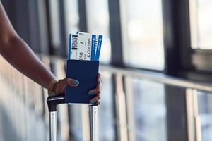 ung afrikansk amerikan kvinna passagerare i tillfällig kläder är i flygplats med biljetter foto