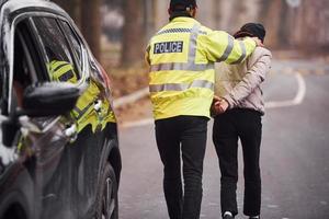 polis officer i grön enhetlig fångad bil stöld på de väg foto